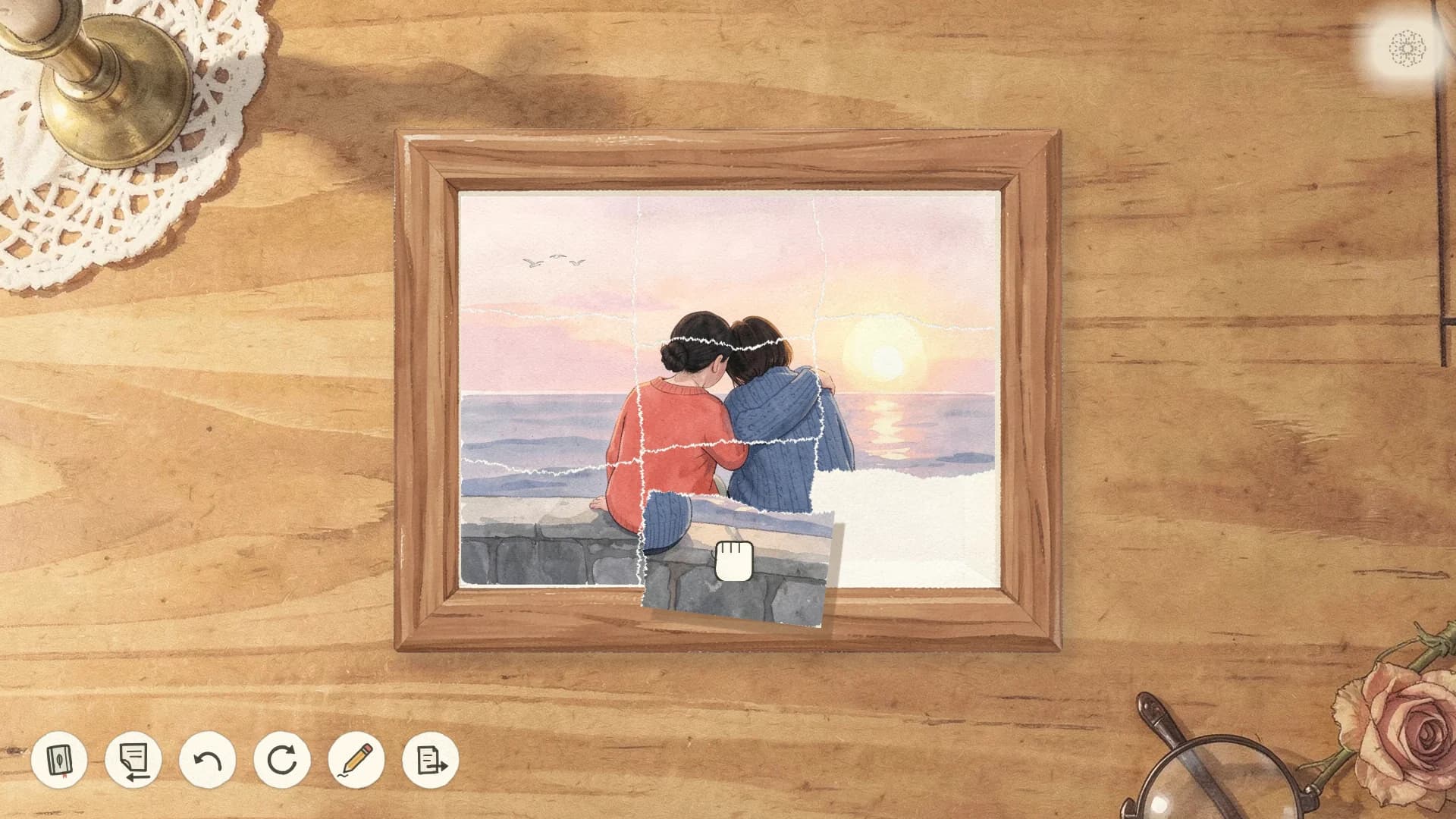 A torn photo of two people sitting on a sea wall at sunset, in a frame on a wooden table, its last piece being carried into place